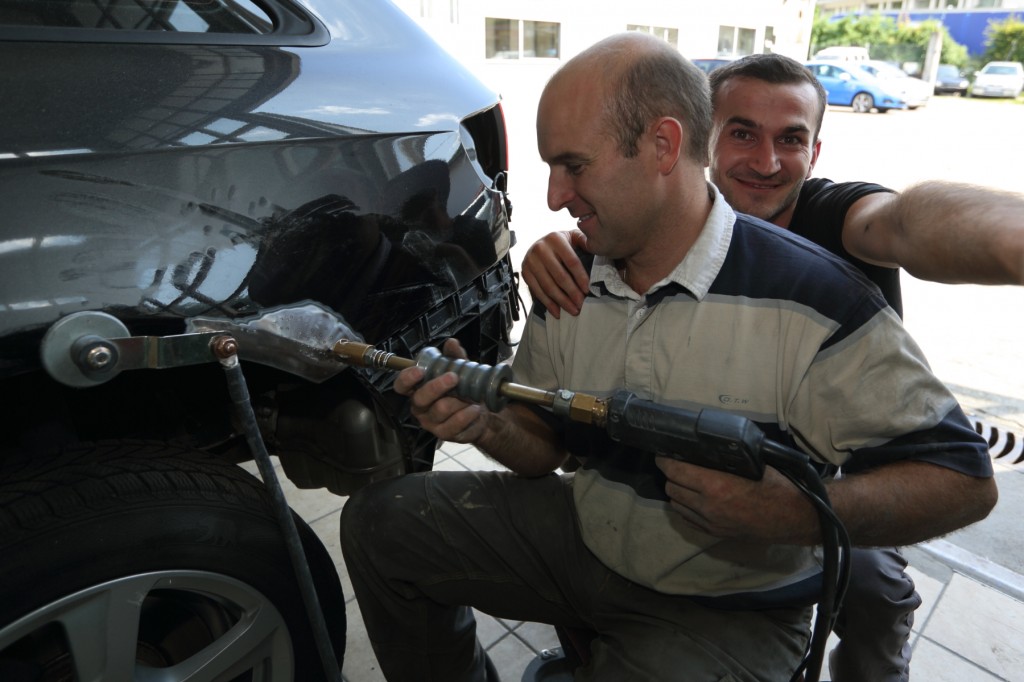Notre carrossier entrain de redresser une aile au tire-clou